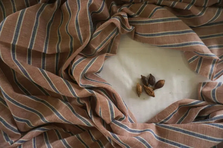 Striped fabric draped over a white surface with small brown objects on it
