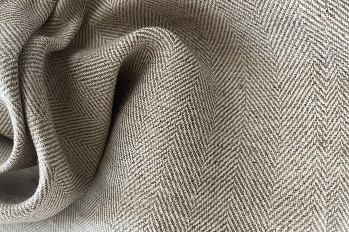 Close-up of herringbone patterned fabric in beige and gray tones.