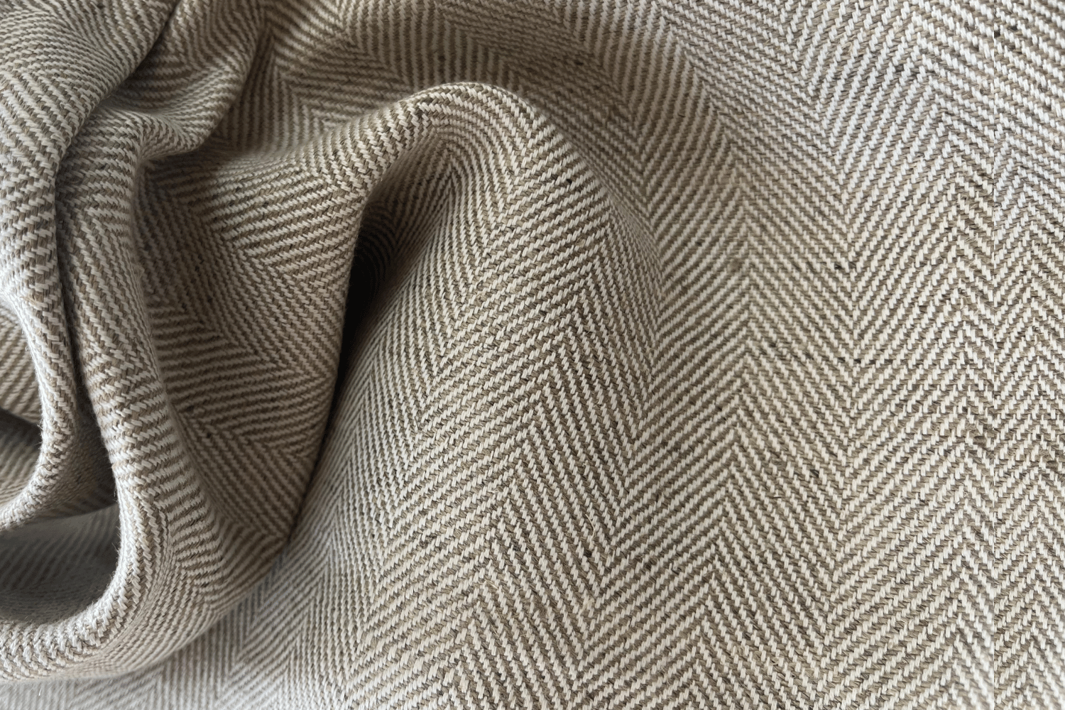 Close-up of herringbone patterned fabric in beige and gray tones.