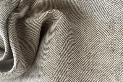 Close-up of herringbone patterned fabric in beige and gray tones.