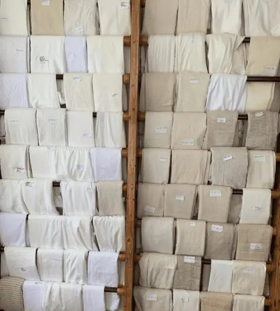 Rack displaying a variety of beige and white fabric swatches. organic white fabrics